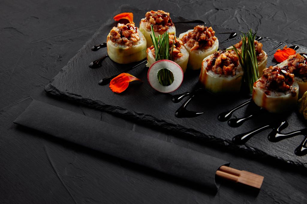 köstliche Sushi-Rolle mit cremigem Aal und Kimchi-Mayonnaise auf Schiefertafel und Essstäbchen   - Foto, Bild