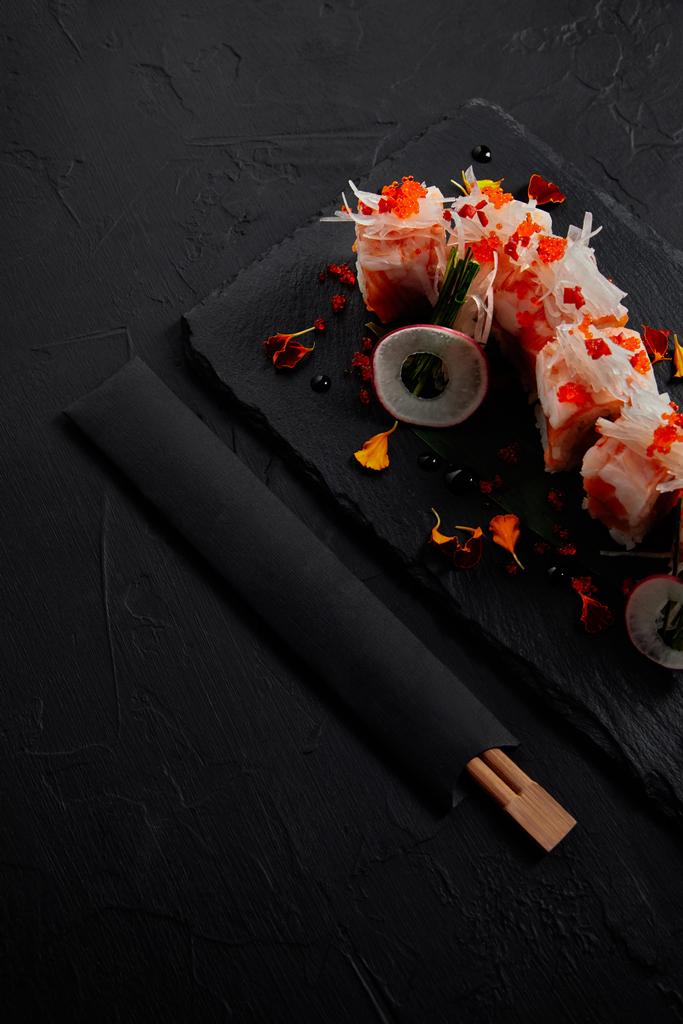 gastronomische roll in mamenori met garnalen, zalm en avocado op leisteen bord en eetstokjes  - Foto, afbeelding