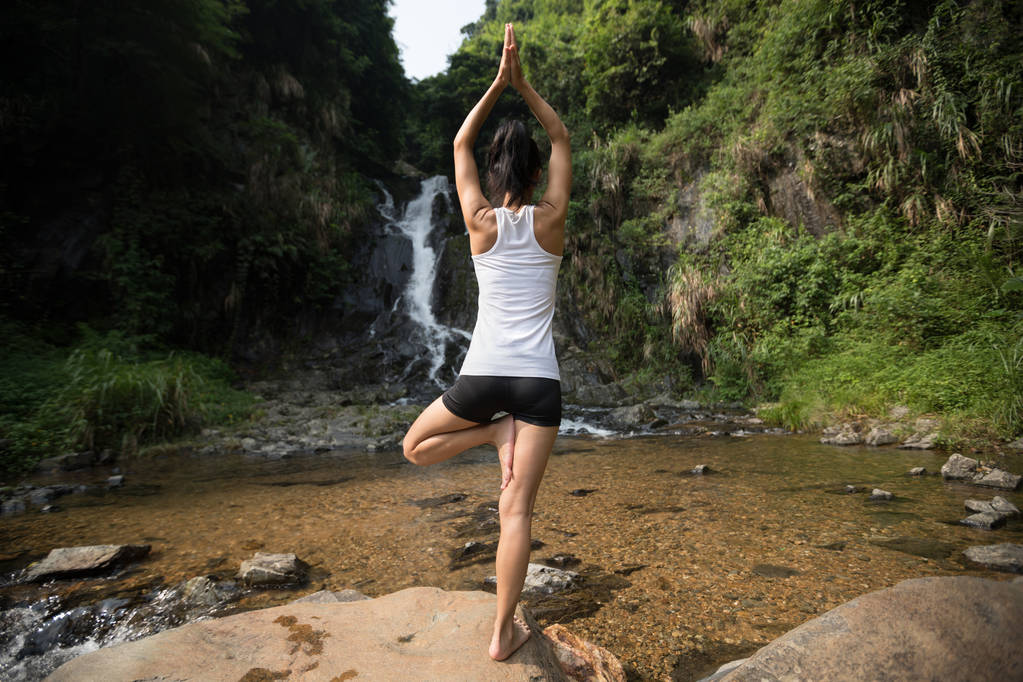 Młoda kobieta robi joga w pobliżu wodospadu w lesie - Zdjęcie, obraz