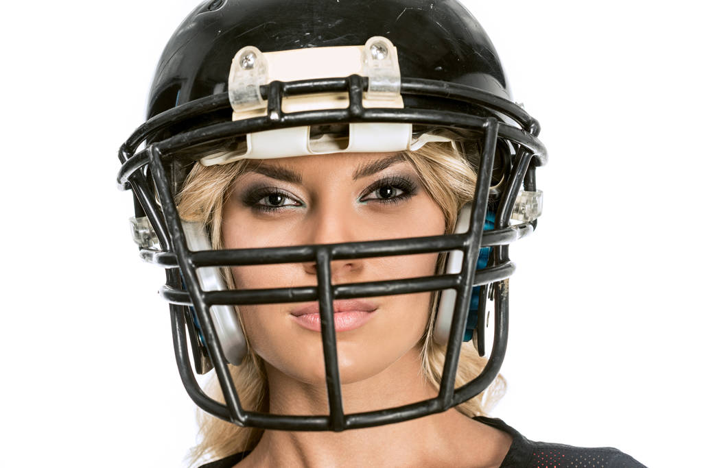 primer plano de mujer joven seria en casco de fútbol americano mirando a la cámara aislada en blanco
 - Foto, Imagen