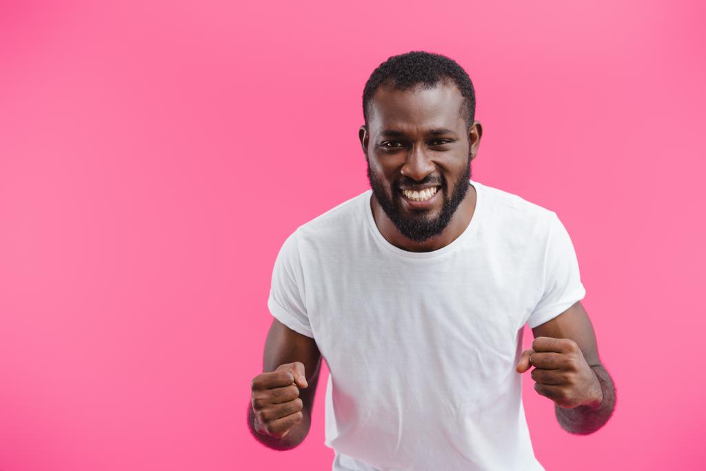 πορτρέτο του χαμογελώντας αφρικανική αμερικανική άνθρωπος που δείχνει τις γροθιές που απομονώνονται σε ροζ  - Φωτογραφία, εικόνα