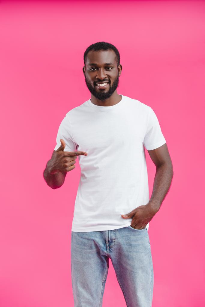 portrait of young smiling african american man pointing away isolated on pink  - Photo, Image