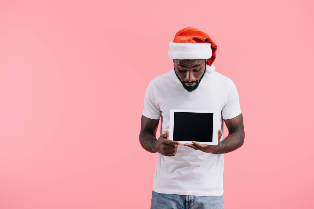 Portret mężczyzny Afroamerykanów w Czapka Mikołaja z tabletu z pustego ekranu na różowym tle - Zdjęcie, obraz