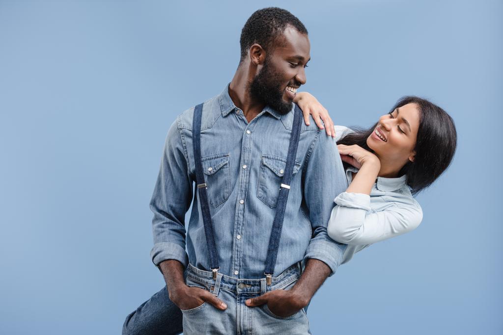 sonriente pareja afroamericana abrazándose y mirándose aislados en azul
 - Foto, imagen