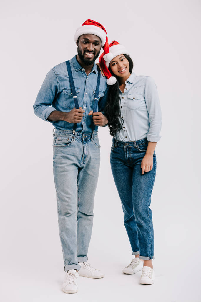 サンタ帽子白で隔離カメラ目線で笑顔のアフリカ系アメリカ人カップル - 写真・画像