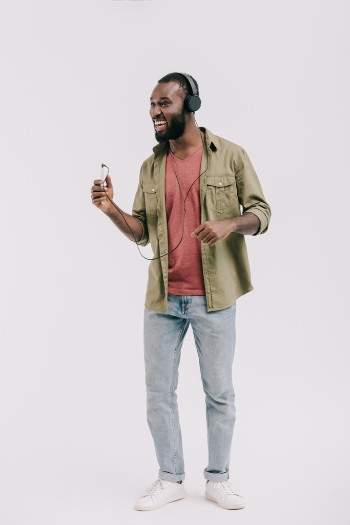 glücklich afrikanisch-amerikanischer Mann hört Musik mit Smartphone und Kopfhörer isoliert auf weiß - Foto, Bild