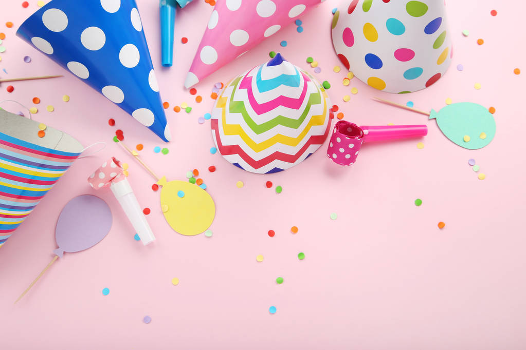 Паперові шапки на день народження з підвісками та конфетті на рожевому фоні
 - Фото, зображення