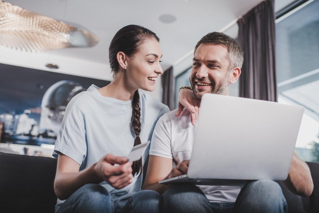 ευτυχισμένο ζευγάρι με φορητό υπολογιστή που κάνει online αγορές με πιστωτική κάρτα στο σπίτι - Φωτογραφία, εικόνα