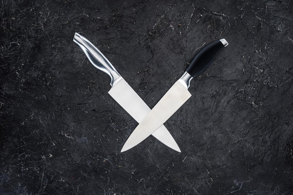 vista dall'alto di due coltelli da cucina disposti su superficie nera
  - Foto, immagini