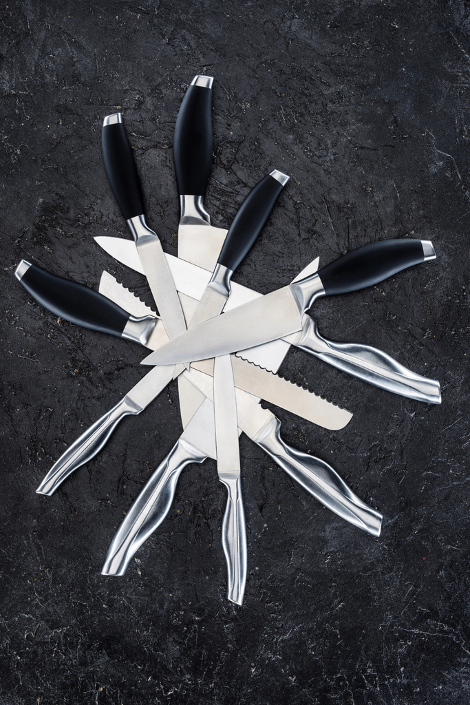вид сверху на различные кухонные ножи, расположенные на черной поверхности
   - Фото, изображение