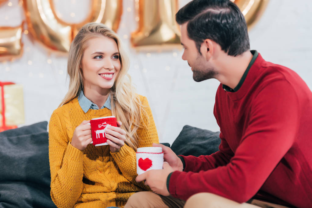 feliz pareja sosteniendo tazas de café de Navidad y mirándose
  - Foto, imagen