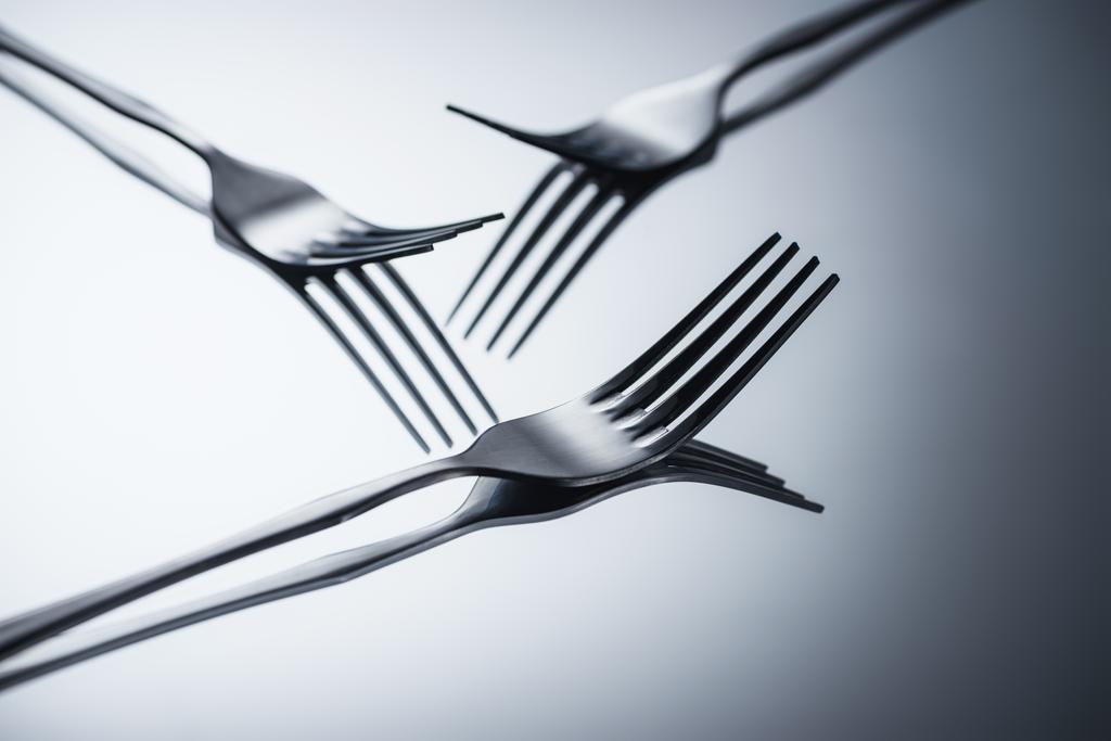 close-up view of three shiny forks reflected on grey   - Photo, Image