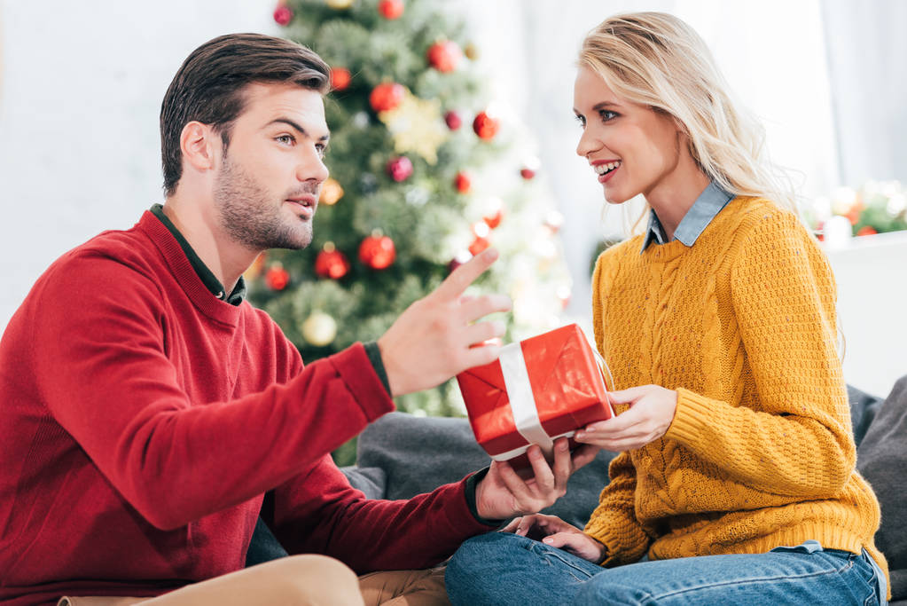 happy young couple gifting present at home with christmas tree - Photo, Image