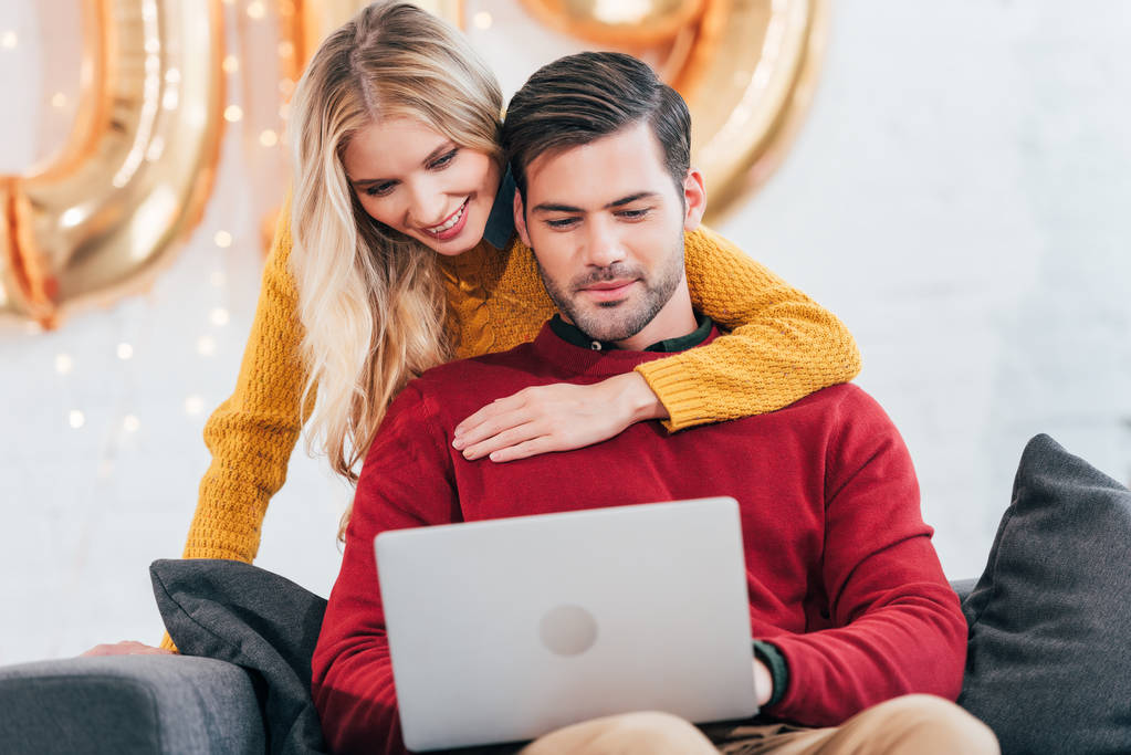 feliz pareja usando el ordenador portátil en casa en año nuevo
 - Foto, imagen