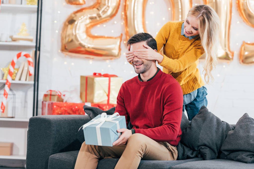 fille fermer les yeux et faire la surprise avec le nouveau cadeau de l'année pour petit ami à la maison avec 2019 ballons dorés
 - Photo, image