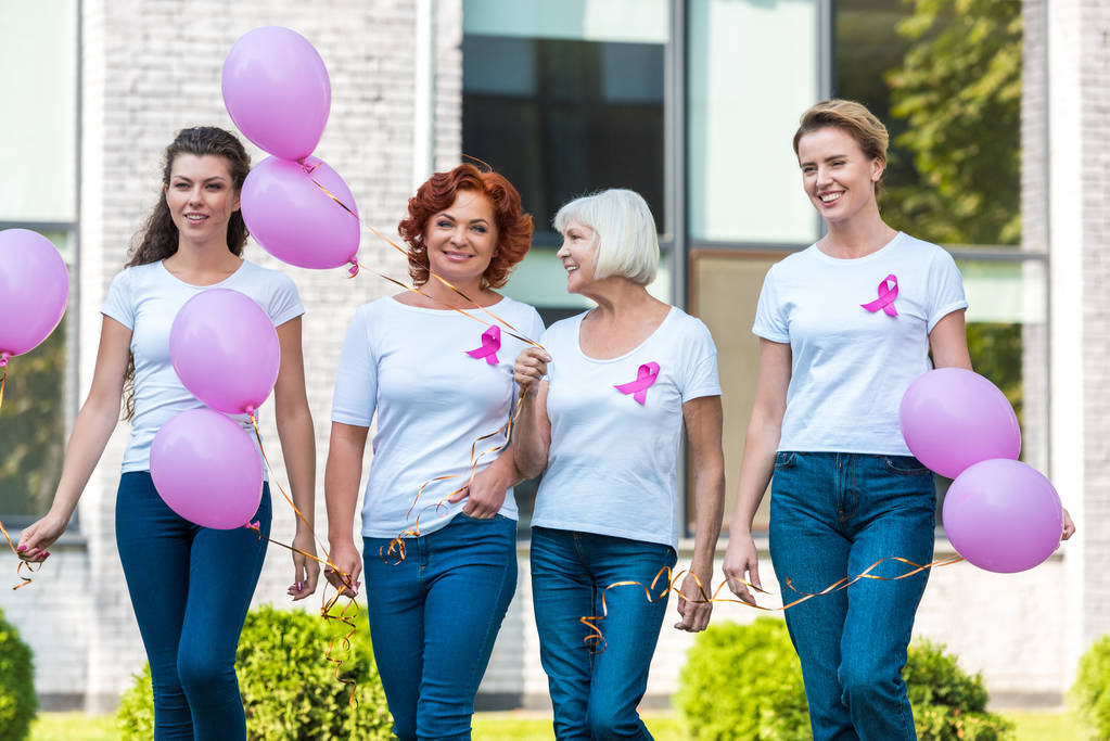 glückliche Frauen, die rosa Luftballons in der Hand halten und gemeinsam gehen, Konzept zur Sensibilisierung gegen Brustkrebs  - Foto, Bild