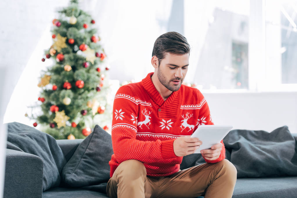 bel homme utilisant tablette numérique, arbre de Noël derrière
 - Photo, image