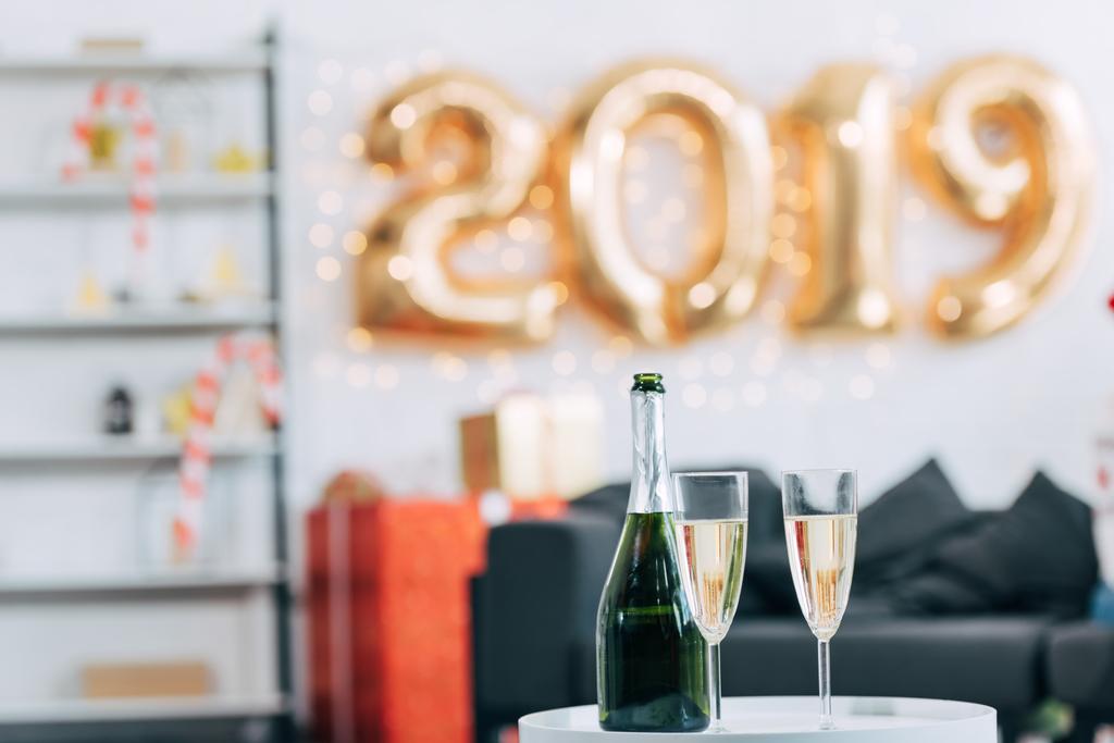 champagnefles en bril met 2019 Nieuwjaar ballonnen op achtergrond - Foto, afbeelding