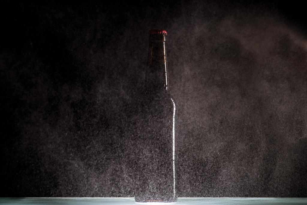 вибірковий фокус пивної пляшки з розбризкуванням води навколо на поверхні на чорному фоні
  - Фото, зображення