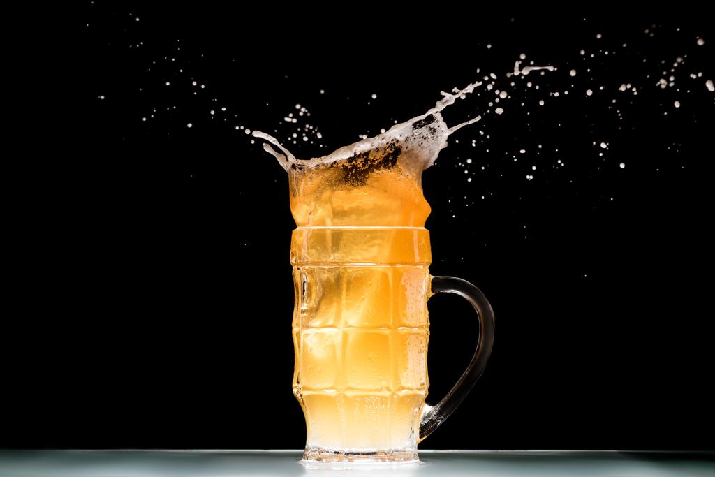 mug of light  beer with foam and splashes at table on black background, minimalistic concept  - Photo, Image