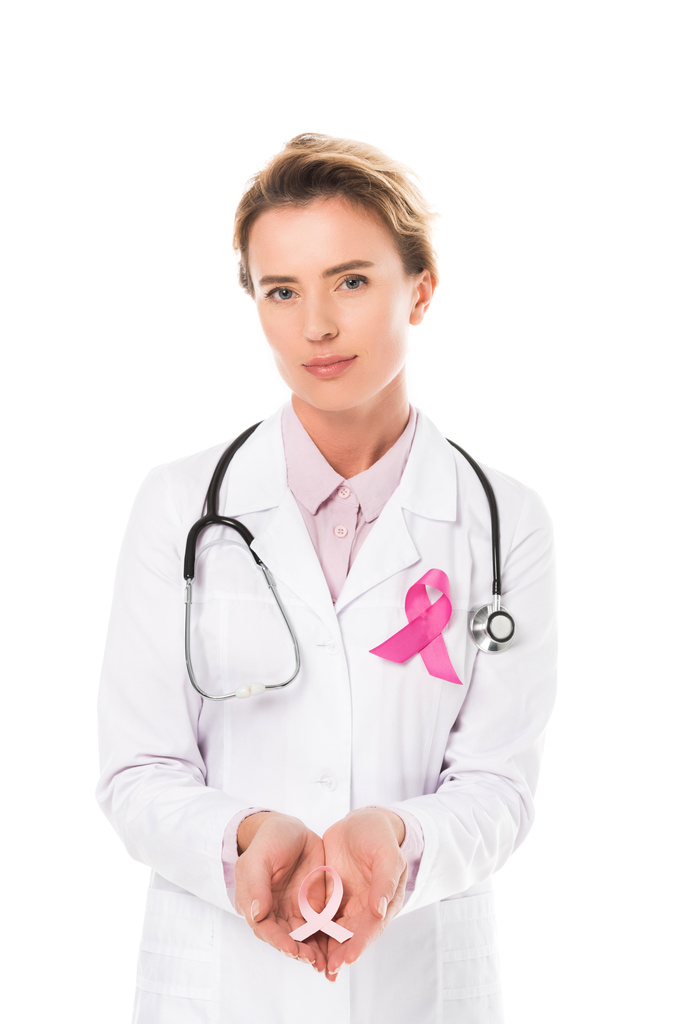 γυναίκα γιατρός με το στηθοσκόπιο κρατώντας ροζ κορδέλα και βλέπουν τα φωτογραφικών μηχανών που απομονώνονται σε λευκό, έννοια συνειδητοποίηση καρκίνου του μαστού - Φωτογραφία, εικόνα
