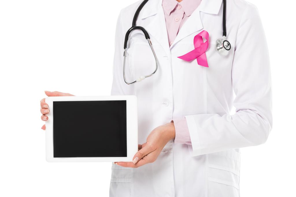 abgeschnittene Aufnahme eines Arztes mit rosafarbener Schleife, der ein digitales Tablet mit leerem Bildschirm hält, isoliert auf weißem, Brustkrebs-Aufklärungskonzept   - Foto, Bild