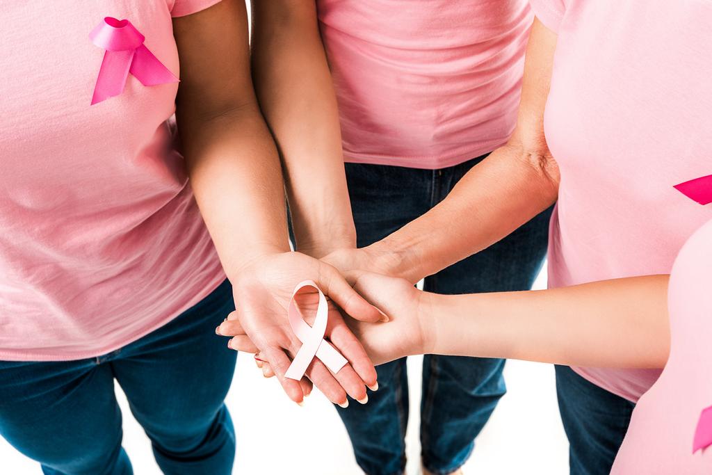 visão parcial de mulheres em camisetas rosa segurando fita de consciência de câncer de mama isolado em branco
  - Foto, Imagem