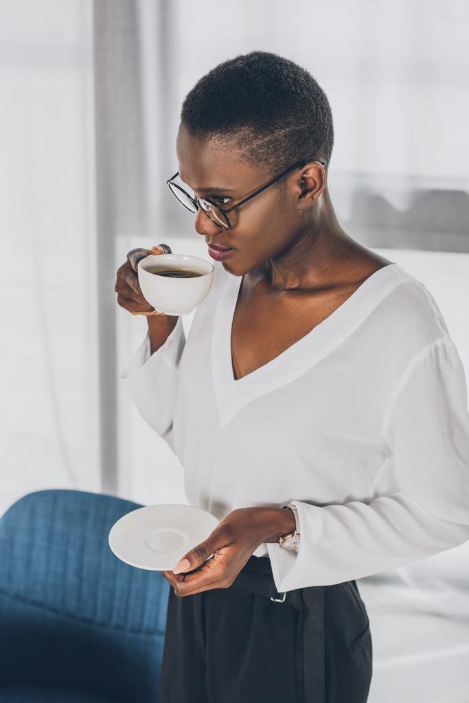 stijlvolle aantrekkelijke Afro-Amerikaanse zakenvrouw drinken koffie in office - Foto, afbeelding