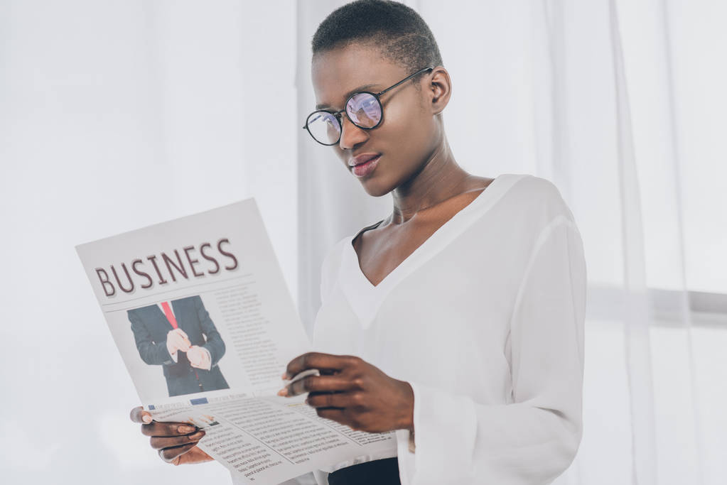 elegante atractiva mujer de negocios afroamericana leyendo periódico en la oficina
 - Foto, imagen