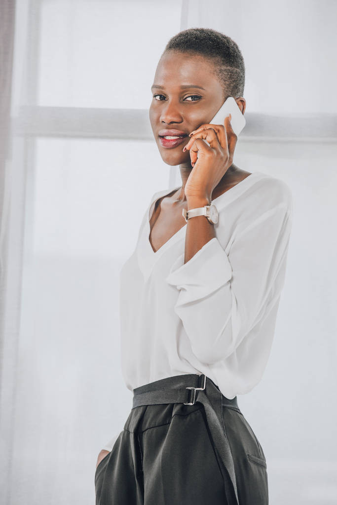 elegante atractiva mujer de negocios afroamericana hablando por teléfono inteligente en la oficina
 - Foto, imagen