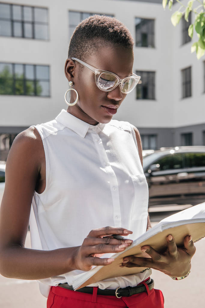 κομψή ελκυστική Αφρικανικός Αμερικανός επιχειρηματίας που βλέπουν έγγραφα στην οδό - Φωτογραφία, εικόνα
