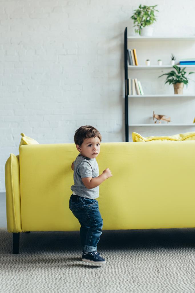 petit garçon jouant près de canapé jaune à la maison
 - Photo, image
