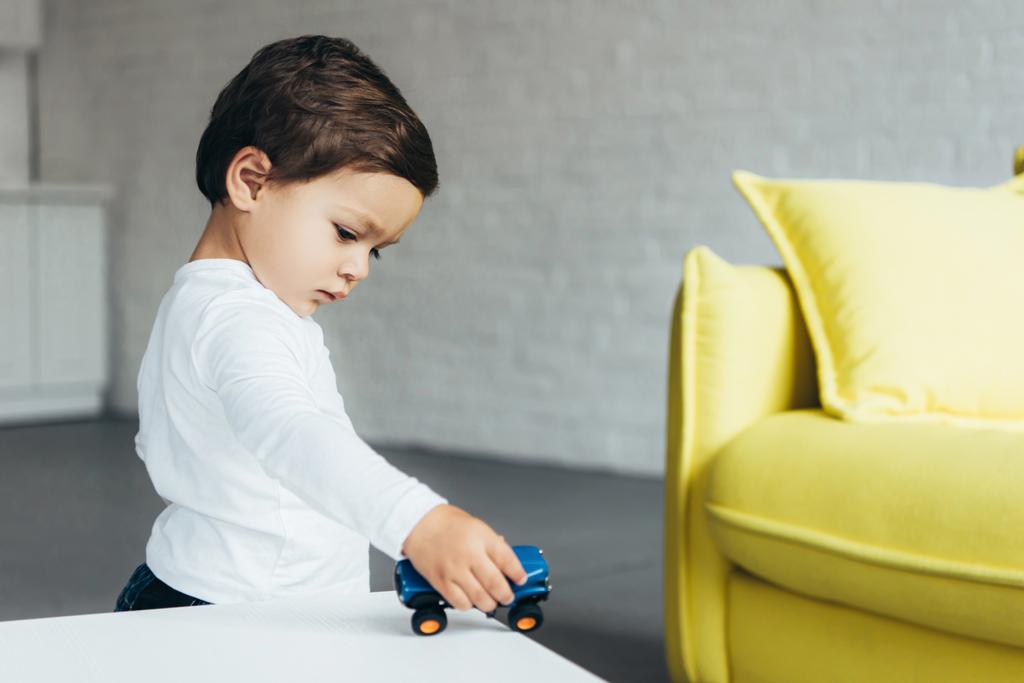 очаровательный ребенок играет с игрушечной машиной дома
 - Фото, изображение