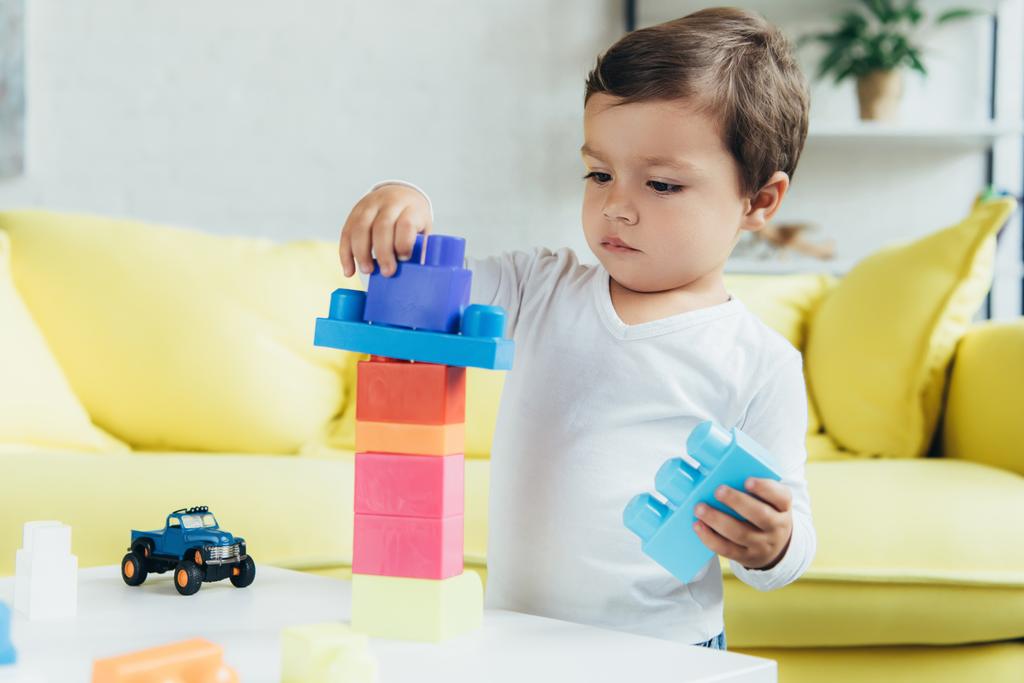 αξιολάτρευτο μικρό αγόρι παίζει με κατασκευή μπλοκ και τα παιχνίδια στο σπίτι - Φωτογραφία, εικόνα