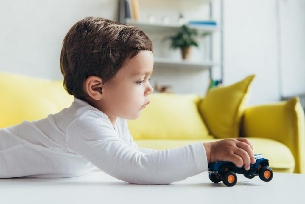 αξιολάτρευτο μικρό αγόρι παίζει με αυτοκίνητο παιχνίδι στο σπίτι - Φωτογραφία, εικόνα