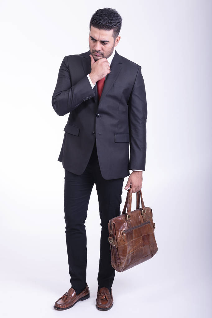 Businessman isolated in white background. Handsome young indian businessman in suit with bag portrait, thinking looks. Full length shot. - Photo, Image