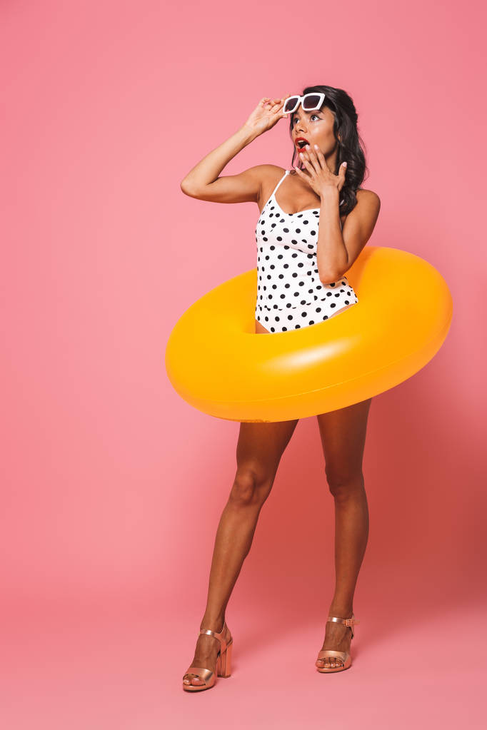 Kuva järkyttynyt nuori nainen uimapuvut poseeraa yli vaaleanpunainen seinä tausta ranta kumi rengas sivuun
. - Valokuva, kuva