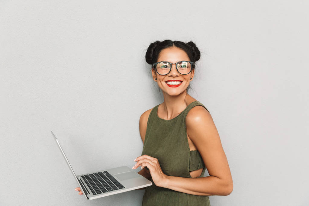 Portrait of a happy young woman isolated, using laptop computer - Photo, Image