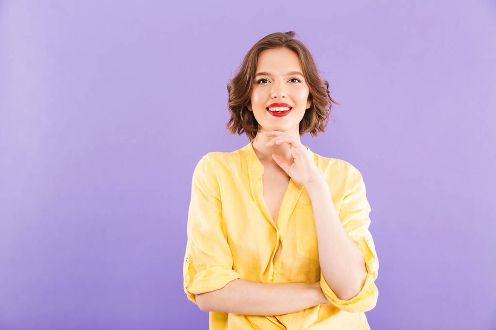 Portrét veselá mladá žena oblečená v letních šatech, přes fialové pozadí při pohledu na fotoaparát - Fotografie, Obrázek