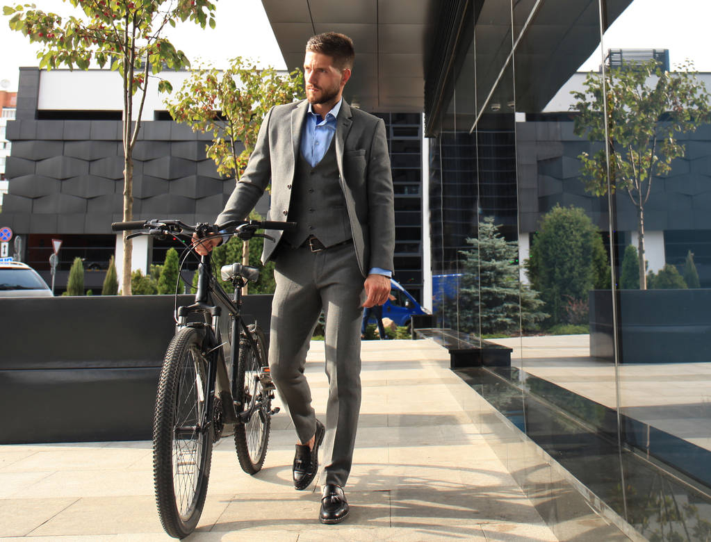 Jovem empresário confiante andando de bicicleta na rua da cidade
. - Foto, Imagem