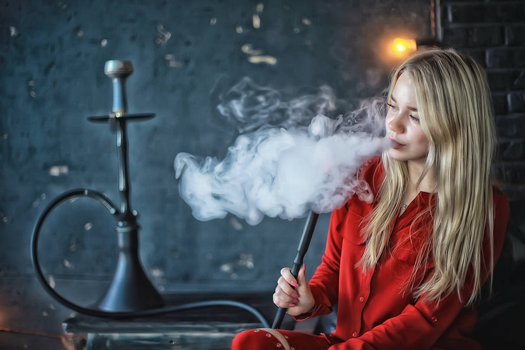 приваблива молода блондинка в червоному одязі курить кальян
 - Фото, зображення