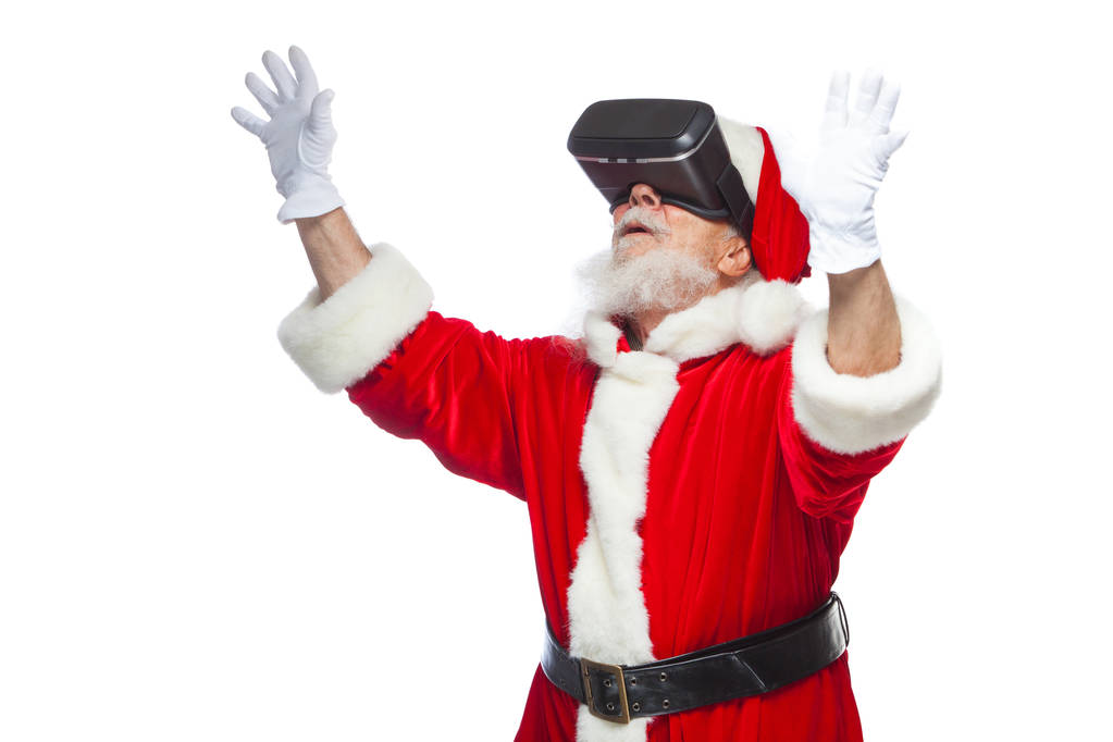 Joulu. Joulupukki musta virtuaalitodellisuus lasit tekee eleitä käsillään. Yllätys, tunne. Uusi teknologia. Eristetty valkoisella pohjalla
. - Valokuva, kuva