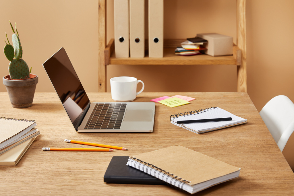 laptop, cadernos e xícara de café em mesa de madeira em casa
 - Foto, Imagem
