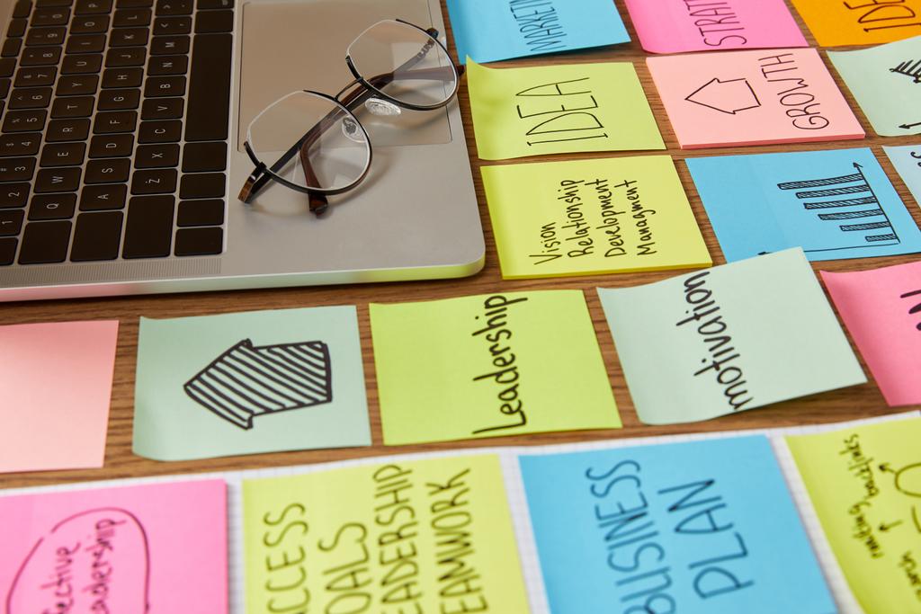 Papieraufkleber mit Geschäftsstrategie und Laptop mit Brille auf Tischplatte - Foto, Bild