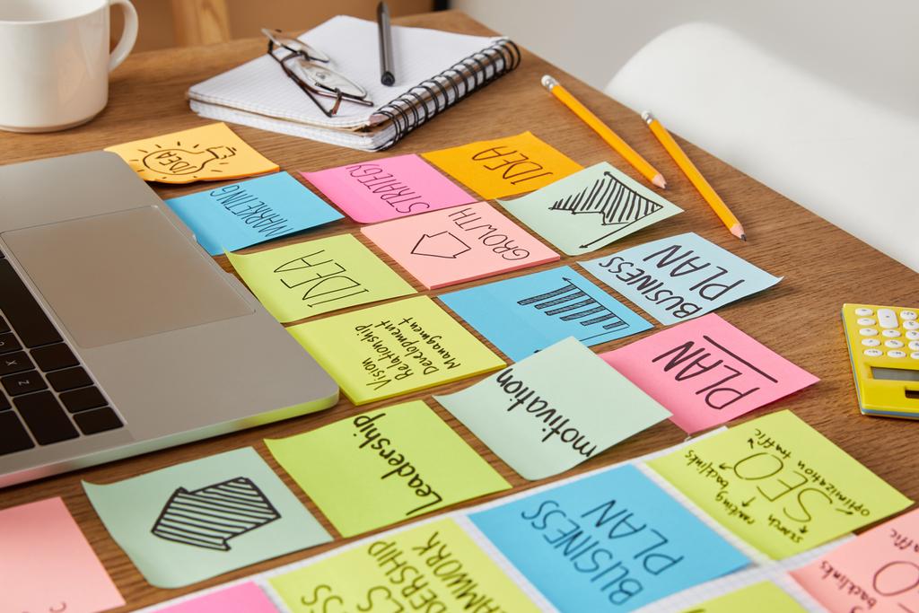 papieren stickers met de bedrijfsstrategie en laptop op tafelblad - Foto, afbeelding