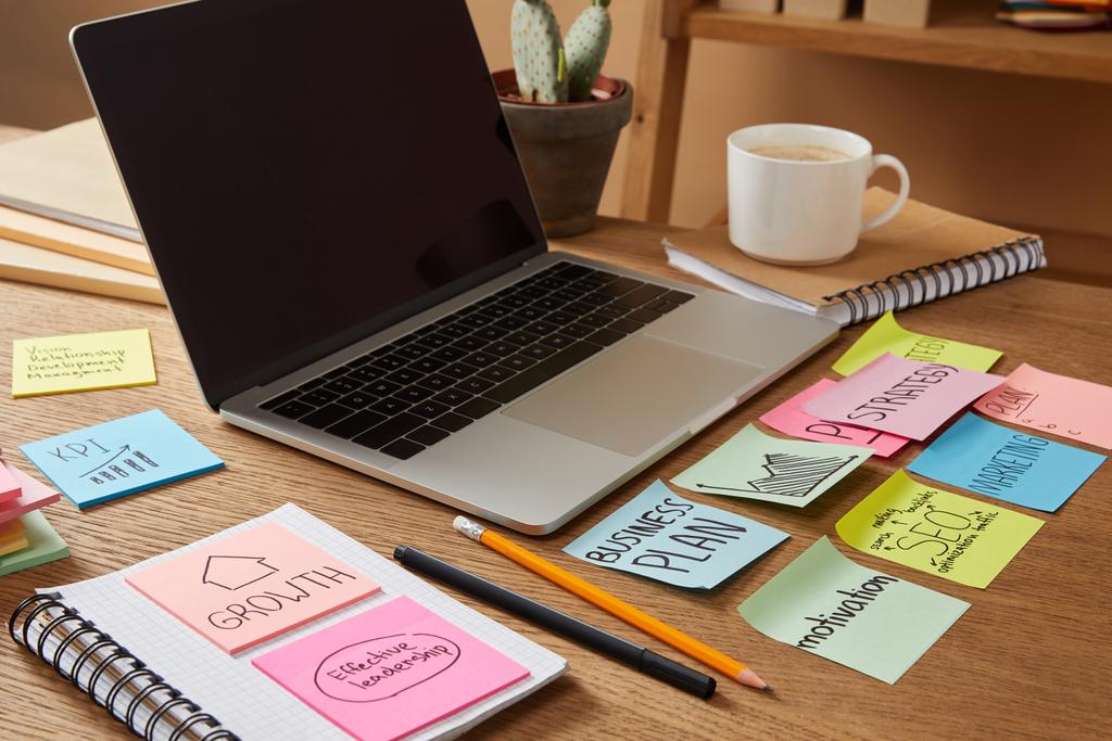 portátil con pantalla en blanco y pegatinas de papel con plan de negocios en la mesa
 - Foto, imagen