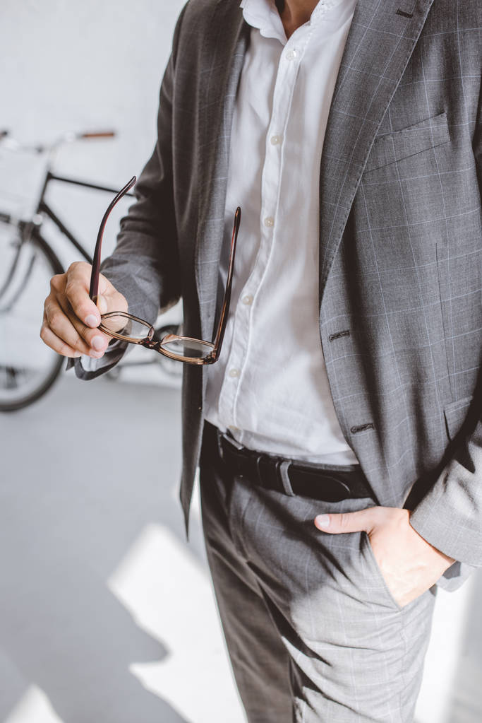 imagen recortada de hombre de negocios sosteniendo gafas en una mano en la oficina
 - Foto, Imagen