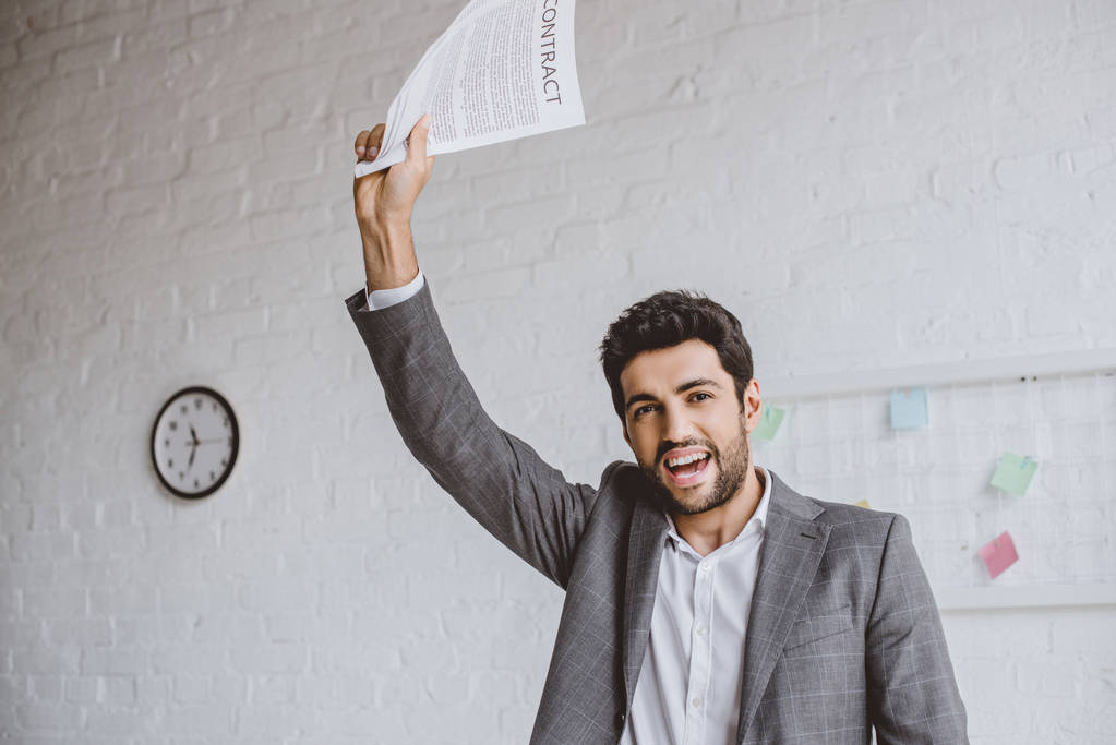 ευτυχισμένος όμορφος επιχειρηματίας που κατέχουν έγγραφα σε σήκωσε το χέρι στο γραφείο - Φωτογραφία, εικόνα