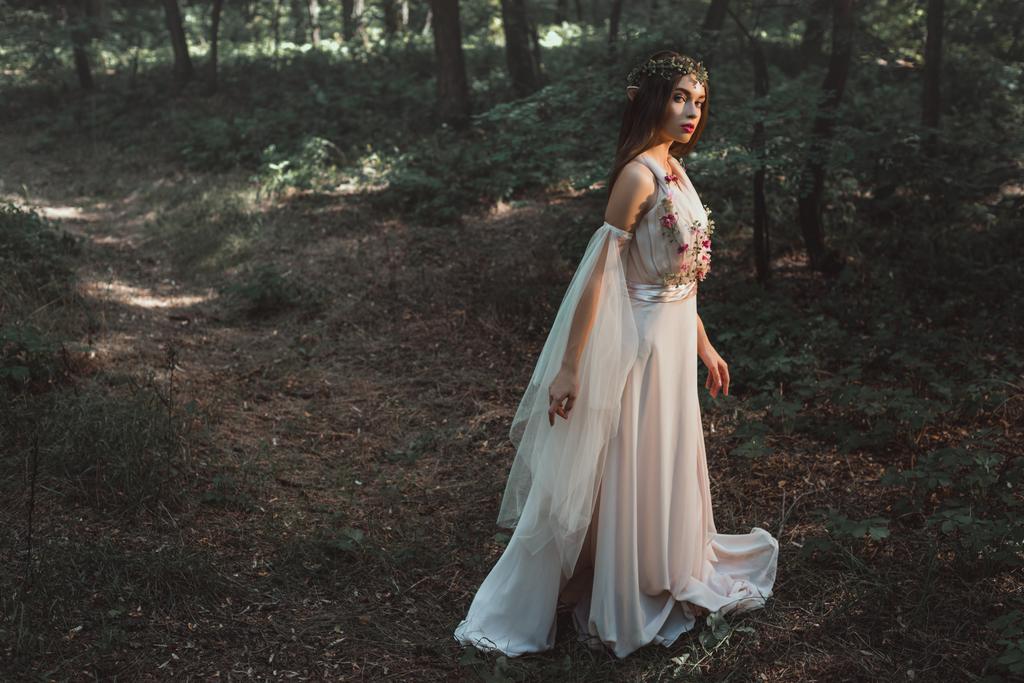 элегантный мистический эльф в платье с цветами прогулки в лесу
 - Фото, изображение