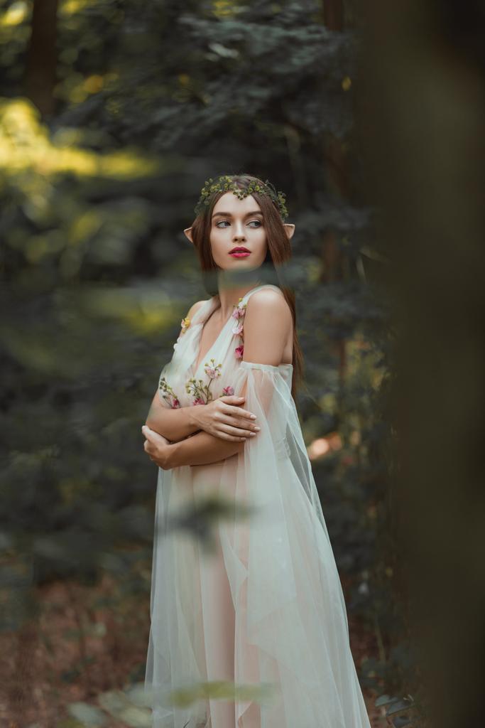 chica atractiva con orejas de elfo caminando en el bosque de fantasía
 - Foto, Imagen